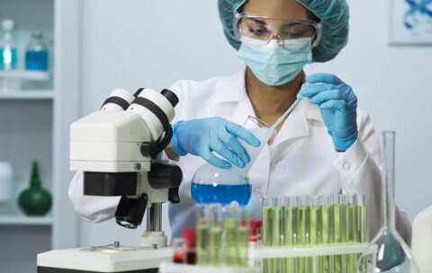Young medic taking blue liquid sample and doing biochemical research, laboratory