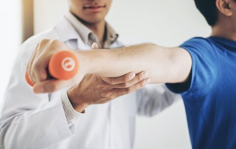 Physiotherapist man giving exercise with dumbbell treatment About Arm and Shoulder of athlete male patient Physical therapy concept